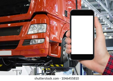 Hand With Phone On A Background Of Truck On A Lift In A Car Service