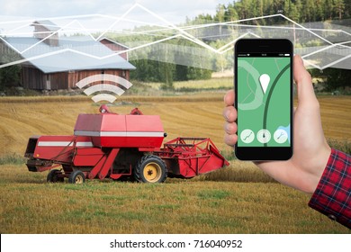 Hand With Phone. On The Screen Control Interface Of The Self Driving Combine Harvester. Internet Of Things In Agriculture.