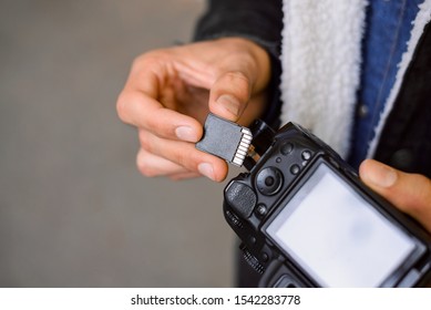 Hand of photographer holding SD memory Card. Male photographer changing SD card of a photo camera outdoors. Young photographer has run out of storage on his memory stick, changes card on his dslr