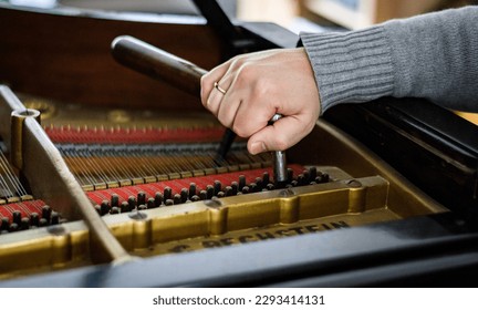 Hand of Pianotuner at Work. Close-up of the hand of a pianotuner using a tool to tune a grand piano.