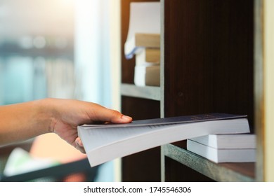 Hand pick up book on shelf. Vintage tone of woman selecting book from a bookshelf.  girl looking for a book in library. 
