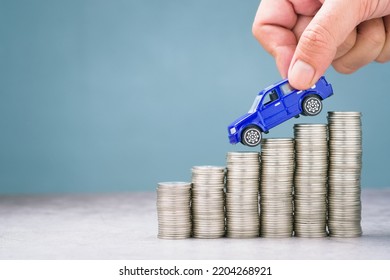 Hand pick the toy car driving down on the descending money, more savings for buying a car, discount, or expenses about car concept - Shutterstock ID 2204268921