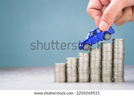 Hand pick the toy car driving down on the descending money, more savings for buying a car, discount, or expenses about car concept