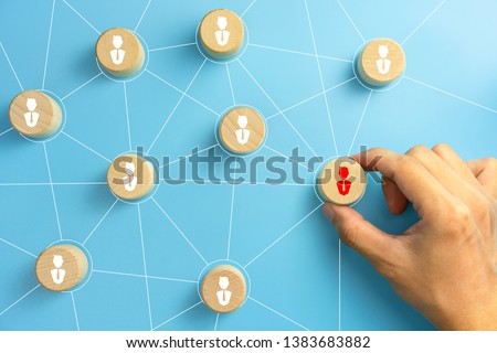 Hand picked a wooden cubes with person icon on blue background, Organisation structure, social network, leadership, team building, recruitment business, management and human resources concepts.