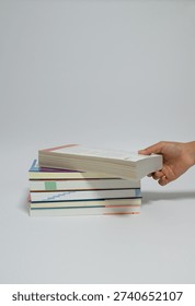 Hand picking up a book from a stack of books on white background