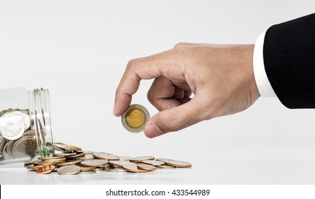 Hand Picking Up Coin From Spilled From Glass Jar