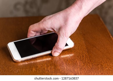 Hand Picking Up Mobile Phone From Table.