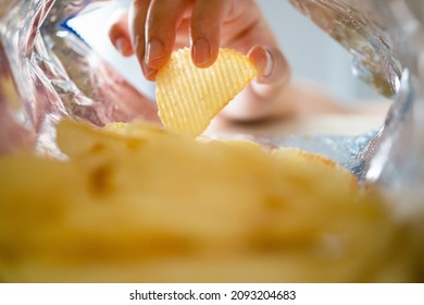 Hand Picking Potato Chips Inside Snack Bag