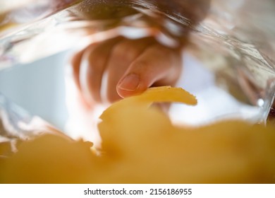 Hand Picking Potato Chips Inside Snack Bag