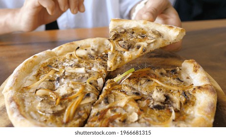 A Hand Picking A Slice Of Vegan Pizza Topped With Lots Of Dairy Free Cheese, Mushrooms And Onions