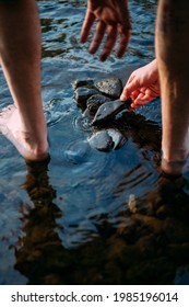 Hand Picking Up Stones And Rocks In A Riverbed