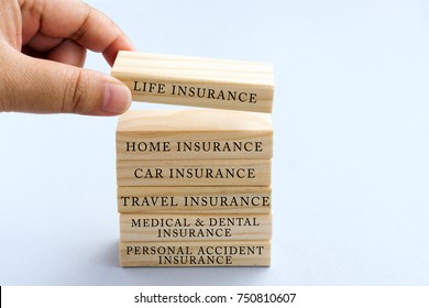 Hand Picking Wood Block With Word Life Insurance. Business Concept Type Of Insurances On Wood Top Block With Word: Life, Home, Car, Travel, Medical And Dental, Personal Accident. 