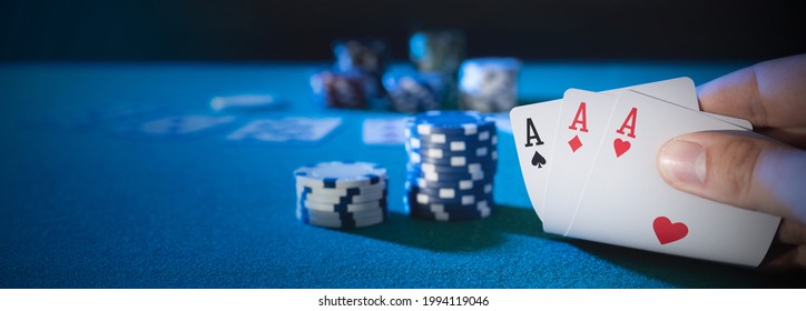 Hand picks up cards, three aces, plays casino poker. Background with copy space
