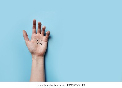 A Hand With A Picture Of A Sad Face. A Symbol Of Depression And Psychological Trauma In Humans
