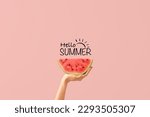 Hand with piece of ripe watermelon and text HELLO, SUMMER on pink background