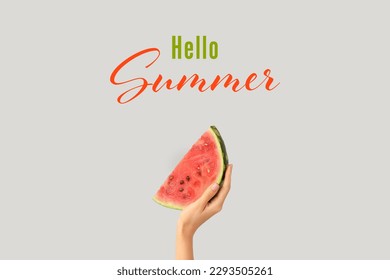 Hand with piece of ripe watermelon and text HELLO, SUMMER on grey background