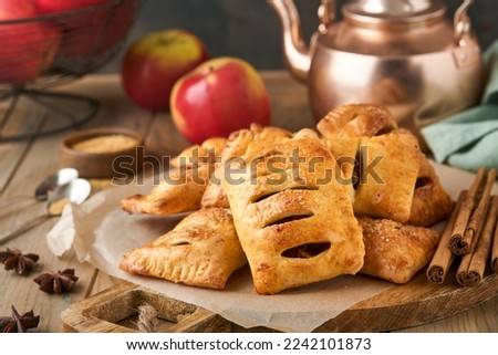 Hand pies. Mini puff pastry or hand pies stuffed with apple and sprinkle sugar powder in wooden plate. Homemade pie snack with crust for breakfast rustic photo. Copy space.