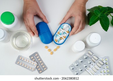 Hand with pills and pillboxes. Top view of six day pill box with pills. Blue pill-box over light marble table. Open pill box and open boxes with pills or vitamins. Pill box for senior patient