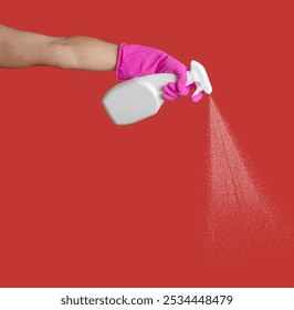 Hand in pink glove sprays detergent on red background. Banner with copy space. Chemical cleaning agents - Powered by Shutterstock