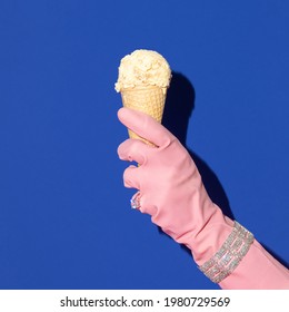 Hand In Pink Rubber Glove With Bracelet And Ring Holding Ice Cream On Bold Navy Blue Background. Retro Style Aesthetic Concept. Creative Summer Fashion Idea.