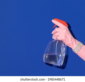 Hand In Pink Rubber Glove With Bracelet And Ring Holding Window Spray On Bold Navy Blue Background. Retro Style Aesthetic Idea. Creative Summer Fashion Concept.