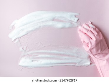 Hand in a pink rubber glove holds a cleaning sponge and wipes a soapy foam on a pink background. Cleaning concept, cleaning service. Flat lay, top view - Powered by Shutterstock