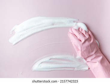 Hand in a pink rubber glove holds a cleaning sponge and wipes a soapy foam on a pink background. Cleaning concept, cleaning service. Flat lay, top view - Powered by Shutterstock