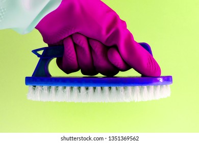 Hand in pink rubber latex glove with blue Handheld floor brush cleaning in on yellow background. the concept of bright spring and renewal, bright mood - Powered by Shutterstock