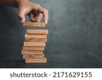 Hand place wooden block stacked concept of prevent collapse or crash of financial business and risk management or strategic planning and insurance.