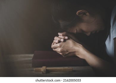 The hand placed on the Bible with his head bowed down. Pray to God. Praying for spiritual beliefs. The power of hope or love and loyalty. Faith in goodness.