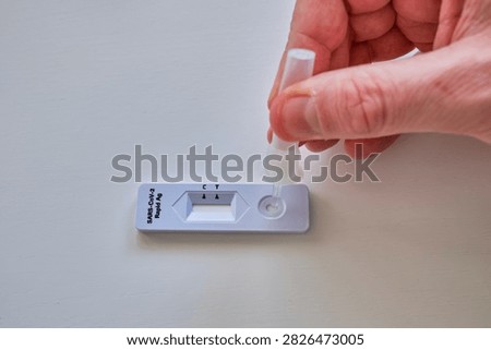 Hand placing liquid sample onto a sars-cov-2 antigen rapid test cassette