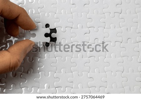 Hand placing missing puzzle piece close up