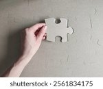 A hand placing a single puzzle piece into a cardboard puzzle, symbolizing problem-solving, creativity and connection