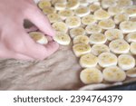 Hand placing sliced banana piaces on dough , closeup, preparing banana pizza