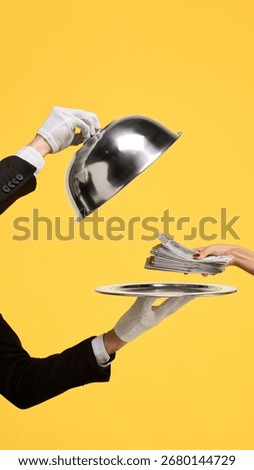 Hand placing stack of money on tray against yellow background. Concept of financial investment, premium banking services, luxury branding, and exclusive business rewards.