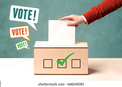 A hand placing a voting slip into a ballot box - Shutterstock ID 468249281