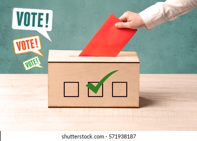 A hand placing a voting slip into a ballot box - Shutterstock ID 571938187