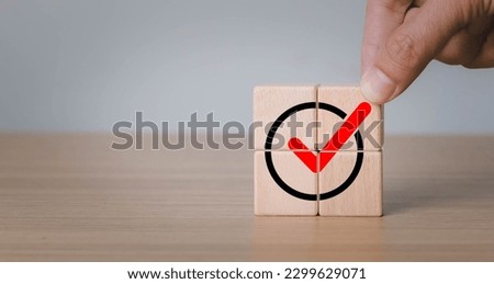 Hand placing wooden cube with green checkmark icon. Goals achievement and business success. Quality and ISO symbol. Do the right thing. Tick and cross signs, approve and disapprove symbol.