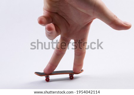Hand is played with mini finger skateboard on white background