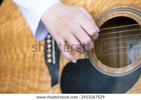 Hand is playing the acoustic guitar, close-up. Fingerpicking, fret, fretboard, guitar lesson