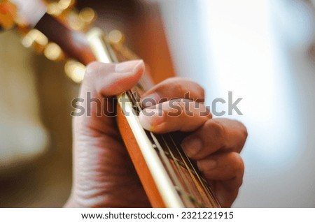 The hand is playing a G chord on the guitar.