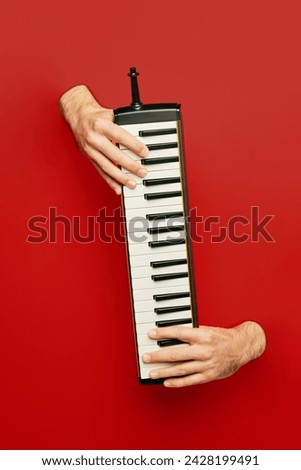 Hand playing a melodic, vertical keyboard against a red background. Poster for a music festival focusing on eclectic and unique instruments. Concept of music, instruments, art, hobby, festival