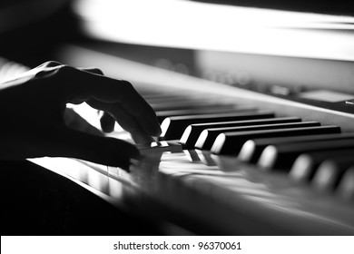 Hand playing on digital piano. Close-up. Small depth of field. Black and white.