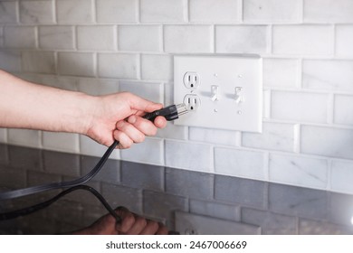Hand Plugging in Electrical Cord into Outlet