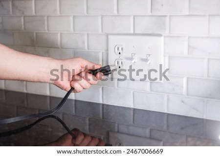 Hand Plugging in Electrical Cord into Outlet