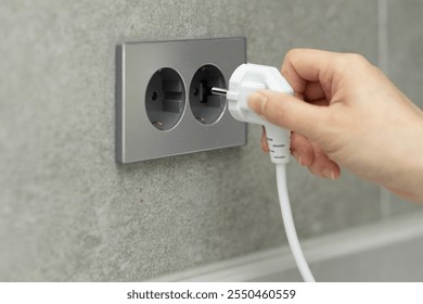 hand plugging out cord from outlet