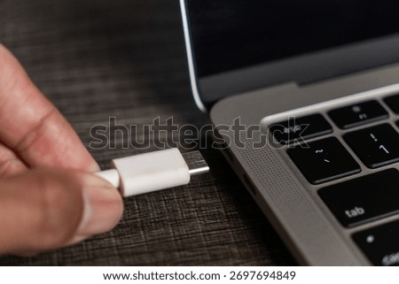Hand Plugging White USB C Cable Connector into Grey Laptop Port