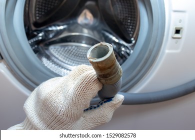 Hand Of A Plumber Holding A Broken Flexible Drain Hose Of Washing Machine, Clogged And Covered With Lime Scale, Dirt Limescale And Rust.