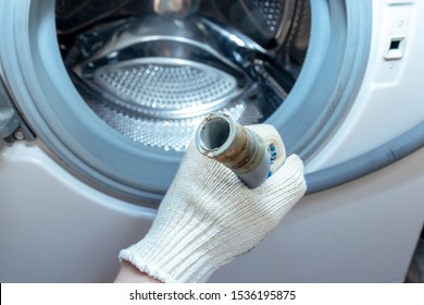 Hand Of A Plumber Holding A Broken Flexible Drain Hose Of Washing Machine, Clogged And Covered With Lime Scale, Dirt Limescale And Rust.