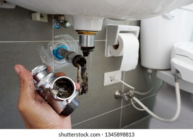 Hand of Plumber holding joints and connections of Basin or sink in a bathroom, Clearing a Clogged Bathroom Sink in a bathroom for unclog a Sink.	                               
